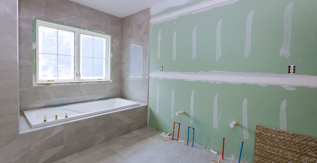 Plombier professionnel installant des canalisations dans une salle de bain en cours de rénovation